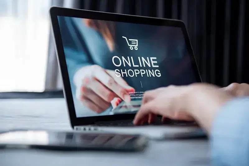 Frau schreibt auf einem Laptop auf dem Online-Shopping steht